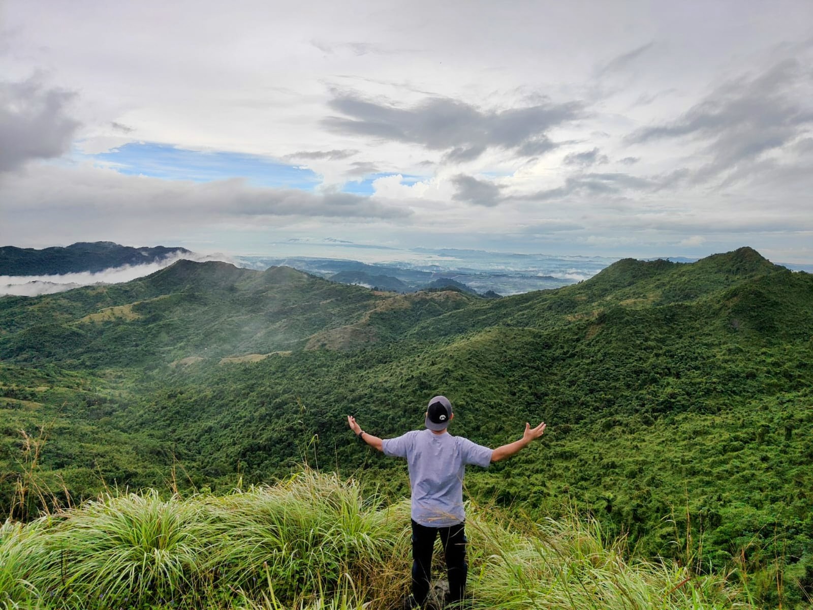 a man standing on a hill with his arms outstretched